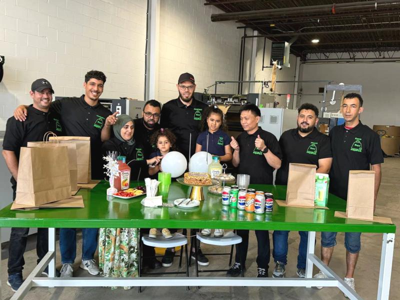 Factory team posing with various finished paper bags and food containers